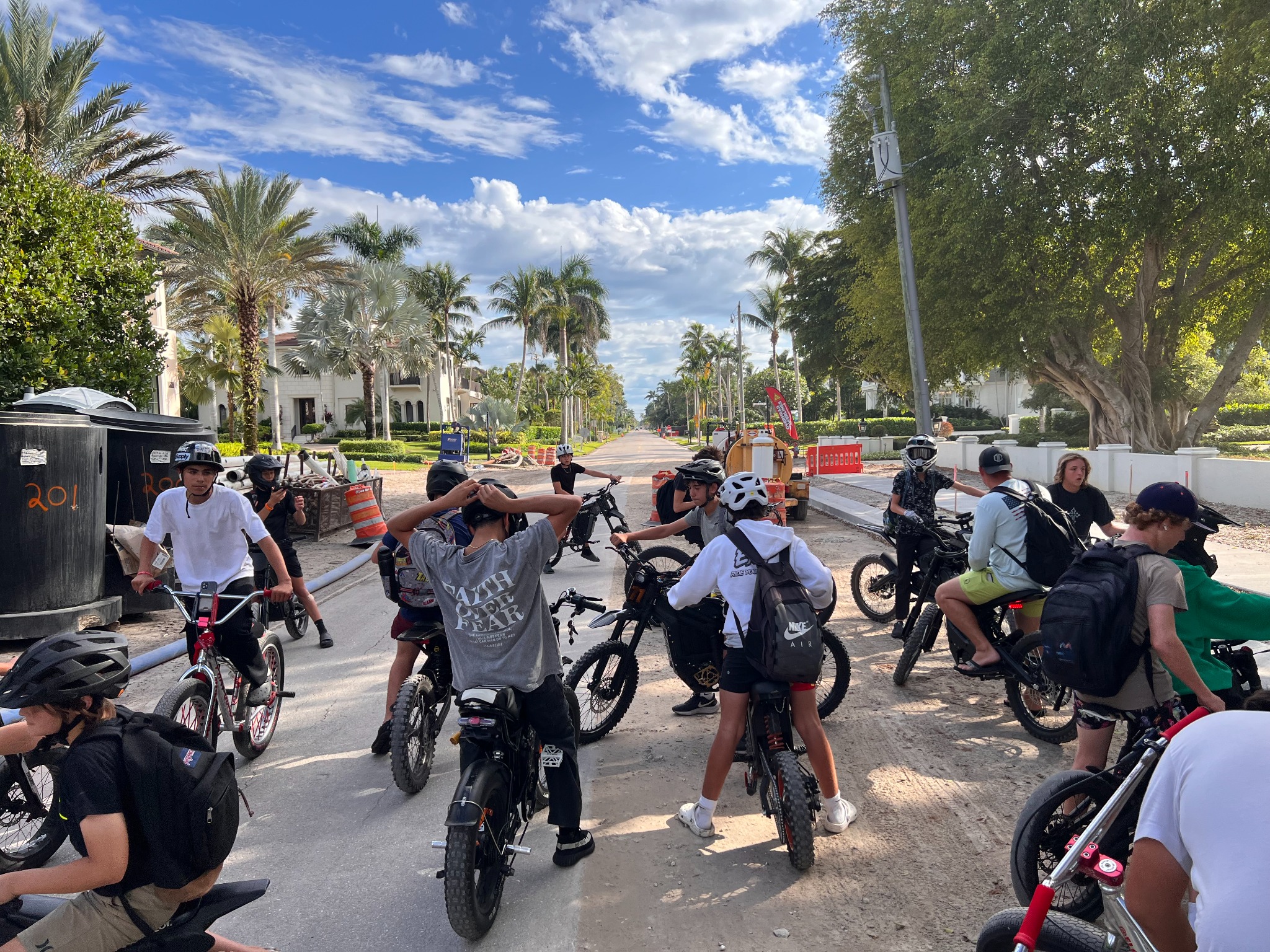 BIKE GNG riders gathered with their bikes on a palm-lined road
